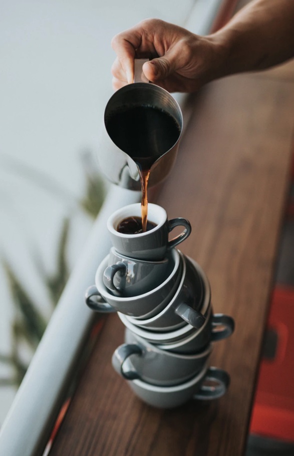 Coffe cups on top of each other and someone pouring a coffee