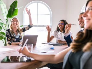 4 smiling people look off to the left in a meeting room