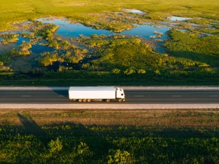 Picture of a white lorry driving on a road next to green fields