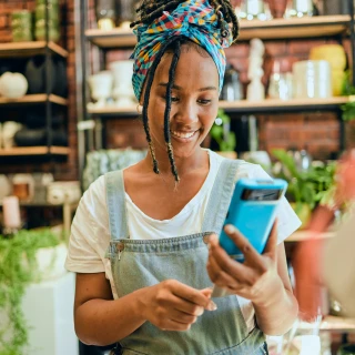 young woman wearing dungarees looks at her phone